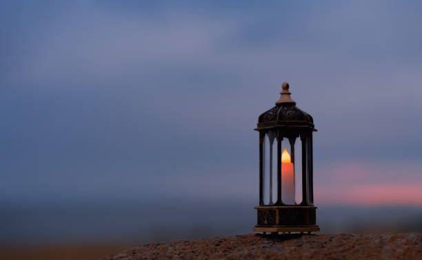 Ramadan Kareem, Arabic lantern with burning candle on sand beach with blurry sunset sky background.Image for Festive greeting card,invitation for Muslim holy month,Eid Mubarak,Eid al Adha,Eid al Fitr stock photo ramadan kareem, linterna árabe con vela encendida en la playa de arena con fondo borroso del cielo de la puesta del sol. imagen para tarjeta de felicitación festiva, invitación para el mes sagrado musulmán, eid mubarak, eid al adha, eid al fitr foto de
