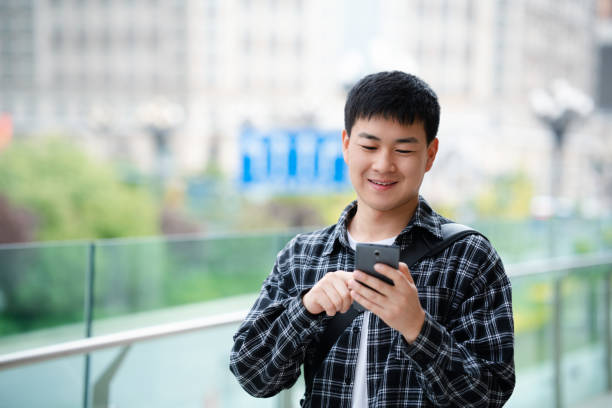 istock Asian handsome young man using smartphone on city street 2157428114