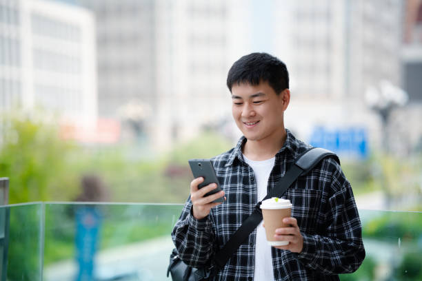 istock Asian handsome young man using smartphone on city street 2157428151