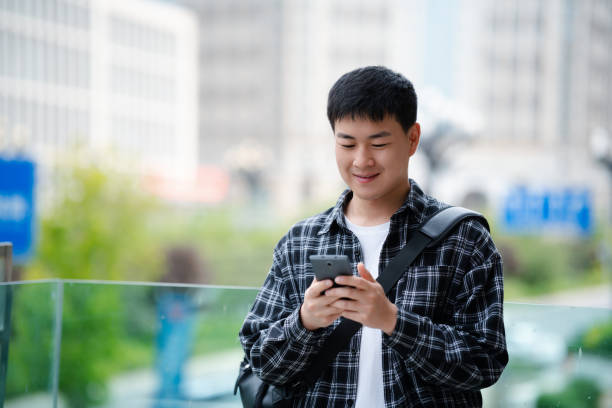 istock Asian handsome young man using smartphone on city street 2157428196