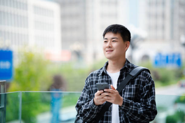 istock Asian handsome young man using smartphone on city street 2157428220