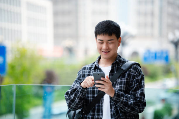 istock Asian handsome young man using smartphone on city street 2157428240
