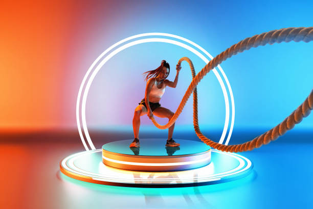 istock Athletic young woman training, doing workout exercises with rope on podium with led circle against colorful gradient background in neon. 3D render 2157435722