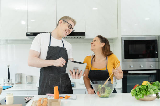 istock A man and woman are in a kitchen, smiling and laughing while preparing a salad 2157436165