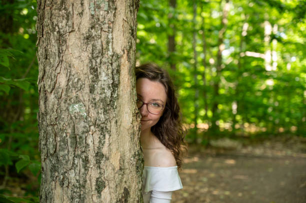 Young woman peeking behind a tree