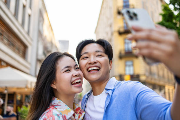 istock Smiling young couple using mobile phone in the city 2157440548