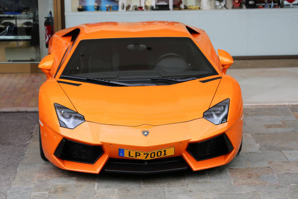 Monte-Carlo, Monaco - May 18, 2016: A striking front view of a bright orange Lamborghini Aventador parked in front of a shop in Monte Carlo. The sleek and aggressive design of this luxury sports car is accentuated by its vibrant color, making it a standout on the street