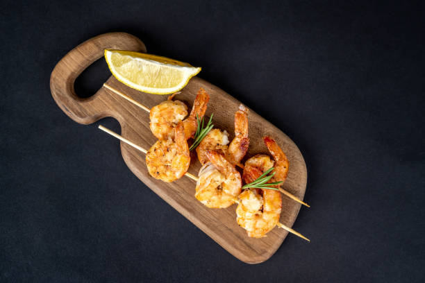 istock Roasted shrimps on skewers arranged on a wooden plate 2157443675