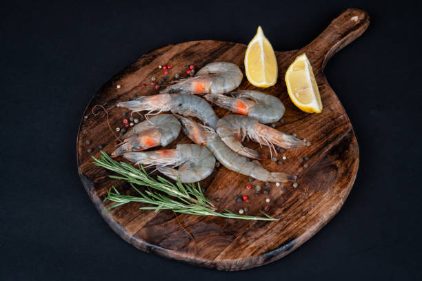 istock Top view of raw shrimps arranged on a wooden board 2157443702