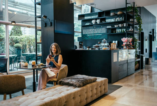 istock Businesswoman using cell phone in hotel cafe 2157445109