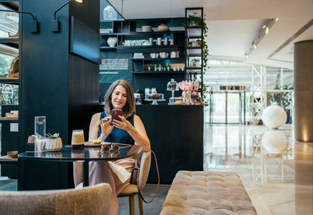istock Businesswoman using cell phone in hotel cafe 2157445114