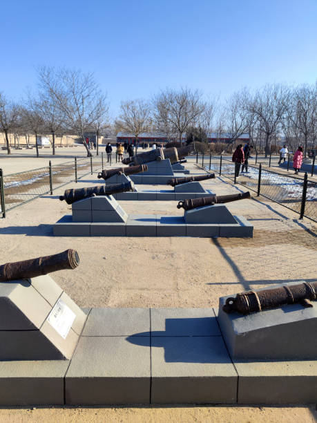 Local people walking by the cannons showed at the West Fort, an old fortress overlooking the Liaodong bay, formerly destroyed by invading Russian and Japanese forces but now partly restored, Yingkou city, Liaoning, China.