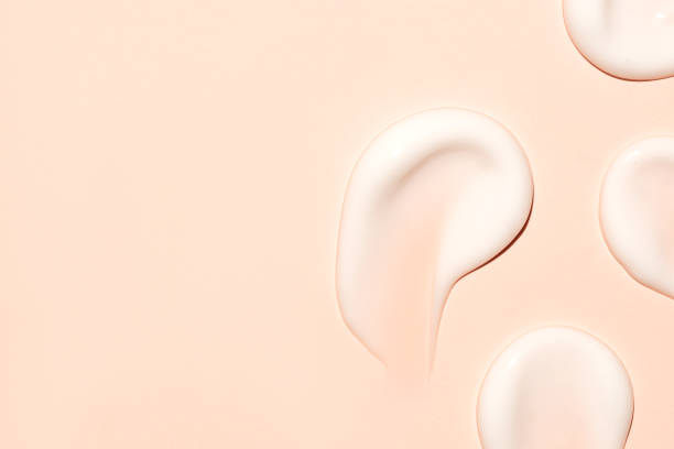 istock white cosmetic face cream or body lotion moisturizer strokes on warm beige background. Hygiene, skincare product with creamy texture. Beauty face cream smear swatch. 2157446930