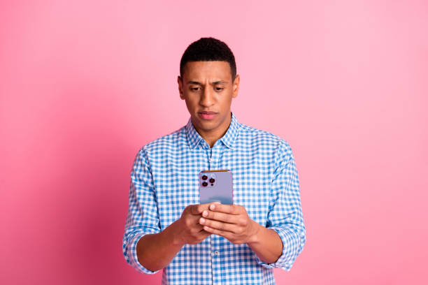 istock Photo of handsome doubtful guy wear plaid shirt communicating modern gadget emtpy space isolated pink color background 2157446952