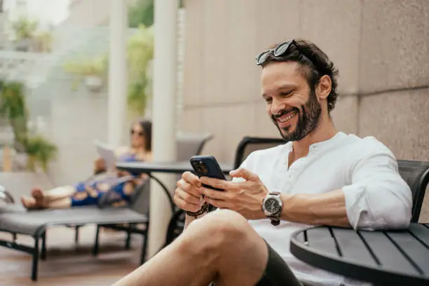 Photo of Man relaxing by the pool using smartphone