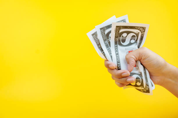 istock Female hands holding banknotes on a yellow background. 2157452741