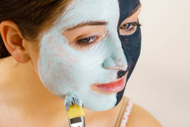 istock Girl black mask on half face apply white mud 2157452816