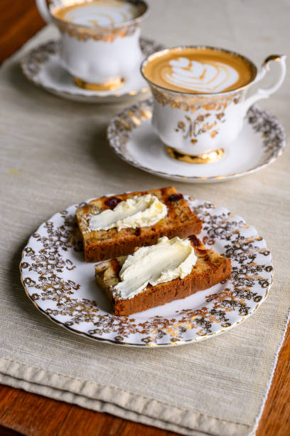 Stock photo shows a delightful English afternoon cream tea featuring golden fruit scones, served with sweet jam and rich clotted cream. This timeless treat offers a perfect blend of flavors, ideal for a relaxing teatime experience
