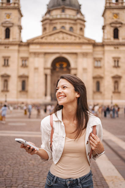 istock Young woman using mobile phone while walking through the Budapest city center 2157454450