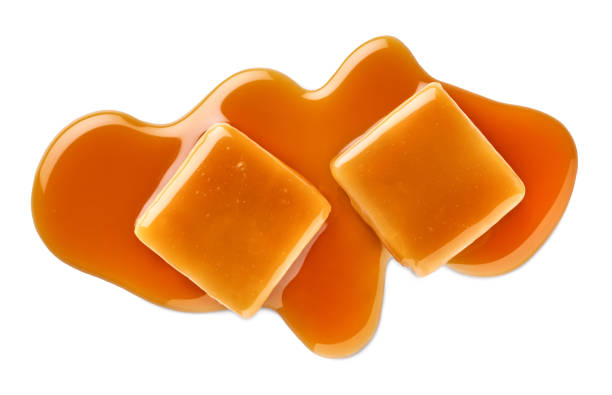istock Two sweet caramel candy cubes topped with caramel sauce on white background 2157456566