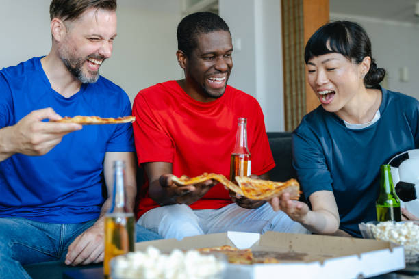 istock Friends eating pizza while watching sports at home 2157456671