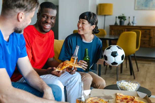 istock Friends eating pizza while watching sports at home 2157456673