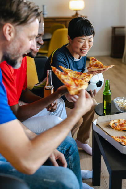 istock Friends eating pizza while watching sports at home 2157456843