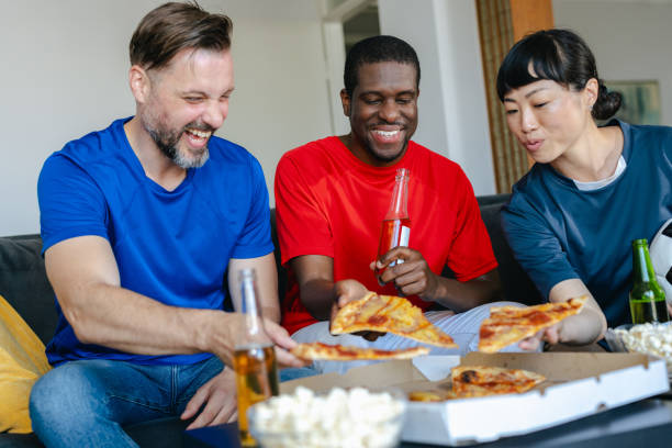 istock Friends eating pizza while watching sports at home 2157456844