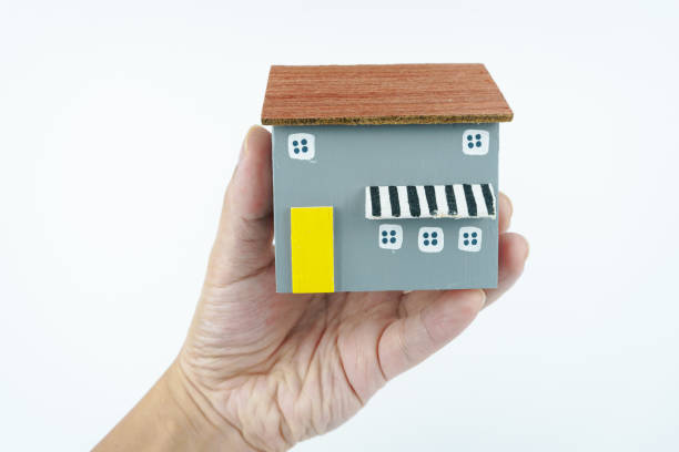 istock hand holding small wooden house on white background. 2157459156