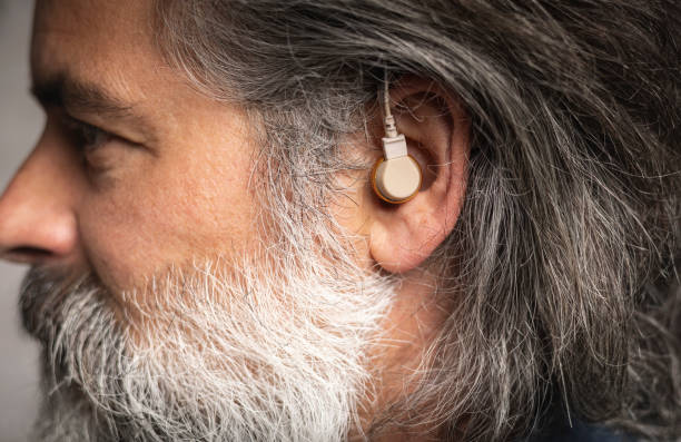 istock Hearing aid in the ear of a middle-aged man 2157460862
