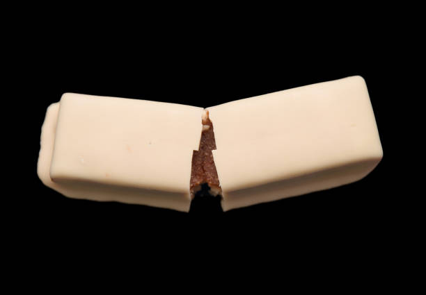 A split white chocolate bar reveals a luscious caramel center against a dramatic black background.