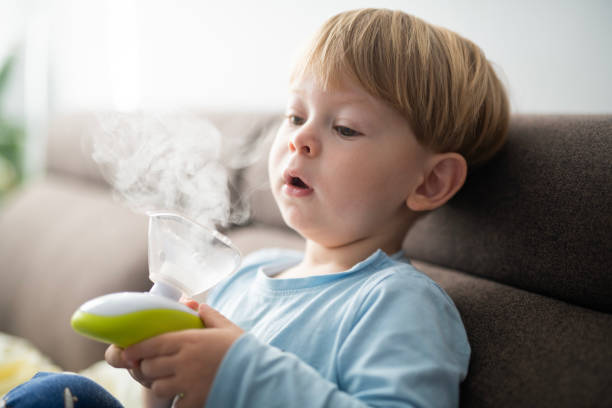 istock Sick toddler at home using inhaler for his respiratory system. 2157463426
