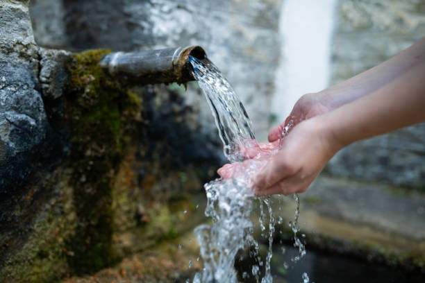 Close-up of hands touching water from drinking fountain.