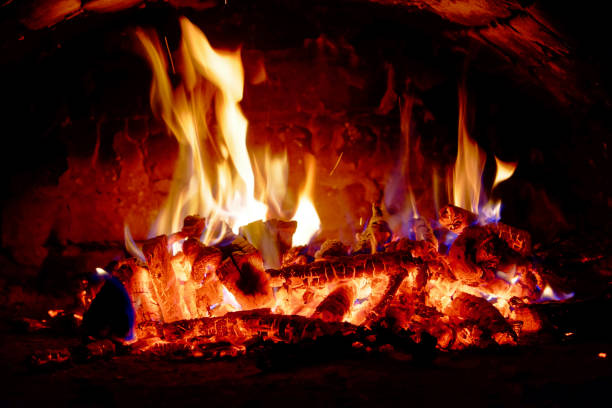 The fire crackles as wood is consumed, emitting light and warmth.