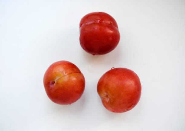 Red plums on a white background.  Plums on a plate. Washed fruits.