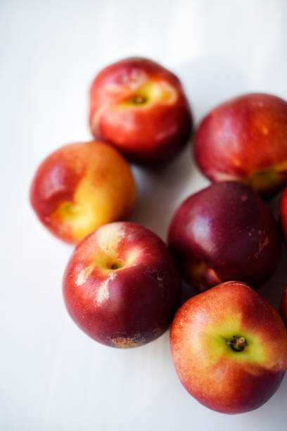 Red and yellow plums on a white background.