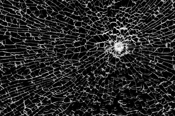 istock Texture of broken tempered glass with a bullet hole and diverging cracks on a black background. Design element. 2157470385