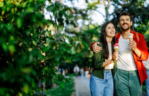 istock Joyful couple holding ice cream in park setting 2157475348