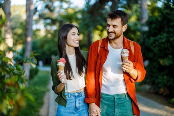 istock Young couple walking with ice cream in park 2157475378