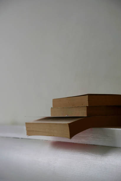 Stack of old books on a bench with pillows in the background.