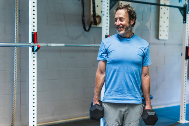 istock A man is smiling while holding two dumbbells in his hands 2157485175
