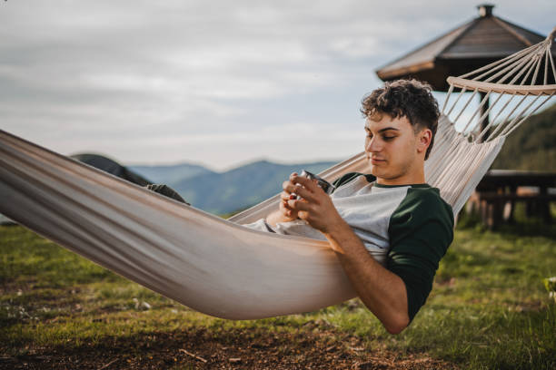 istock Young boy lying down in the hammock with cup of coffee on the mountain 2157488896