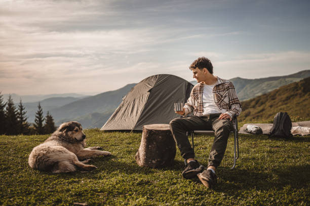 istock Young boy sit in front tent and drink coffee with dog on the mountain 2157488942