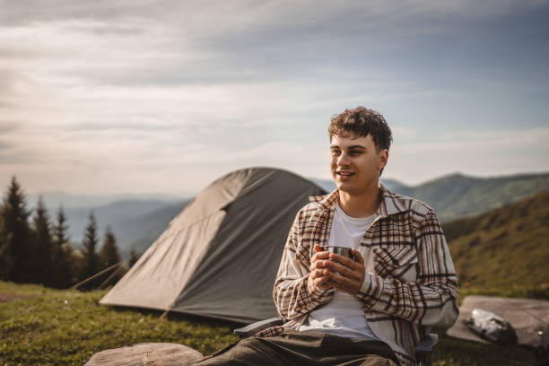 istock Young boy sit in front tent and drink coffee on the mountain 2157489050