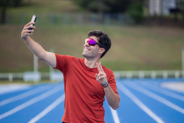 Runner with Sunglasses Takes Selfie with Smartphone During Training on Athletic Track