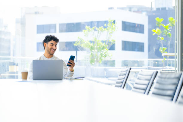 istock Businessman working on a laptop computer and texting or using social media on a mobile phone in the office. 2157499461