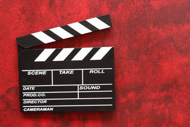 istock Close-up image of black film clapperboard, open hinged clapper stick, mottled red background, elevated view, copy space 2157500036