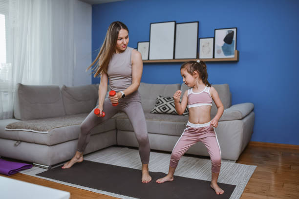 istock Mother Instructing Daughter How To Use Dumbbells For Home Workout 2157501673