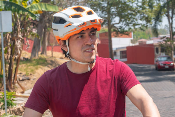 Portrait of a latin man wearing a white helmet, red t-shirt and brown pants and riding his electric bicycle
