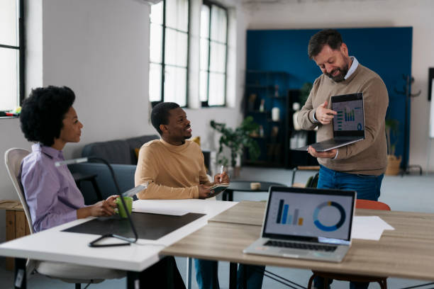 istock Male entrepreneur explaining data on laptop screen to team in office 2157503011
